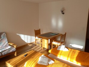 Une pièce avec une table en bois, deux chaises, un canapé et un lit avec des serviettes.