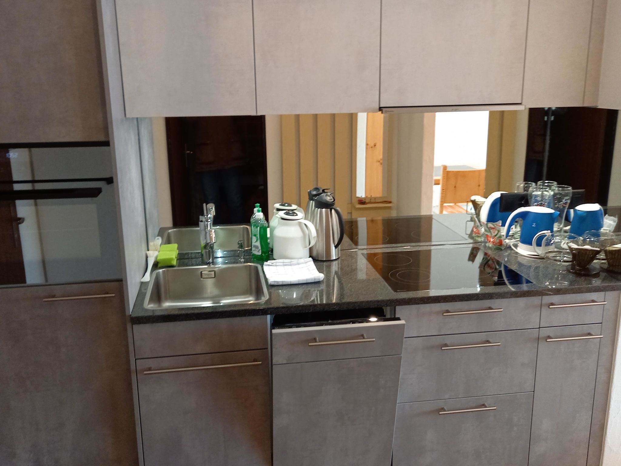 A modern kitchen with stainless steel appliances, a sink, and a countertop with various items.