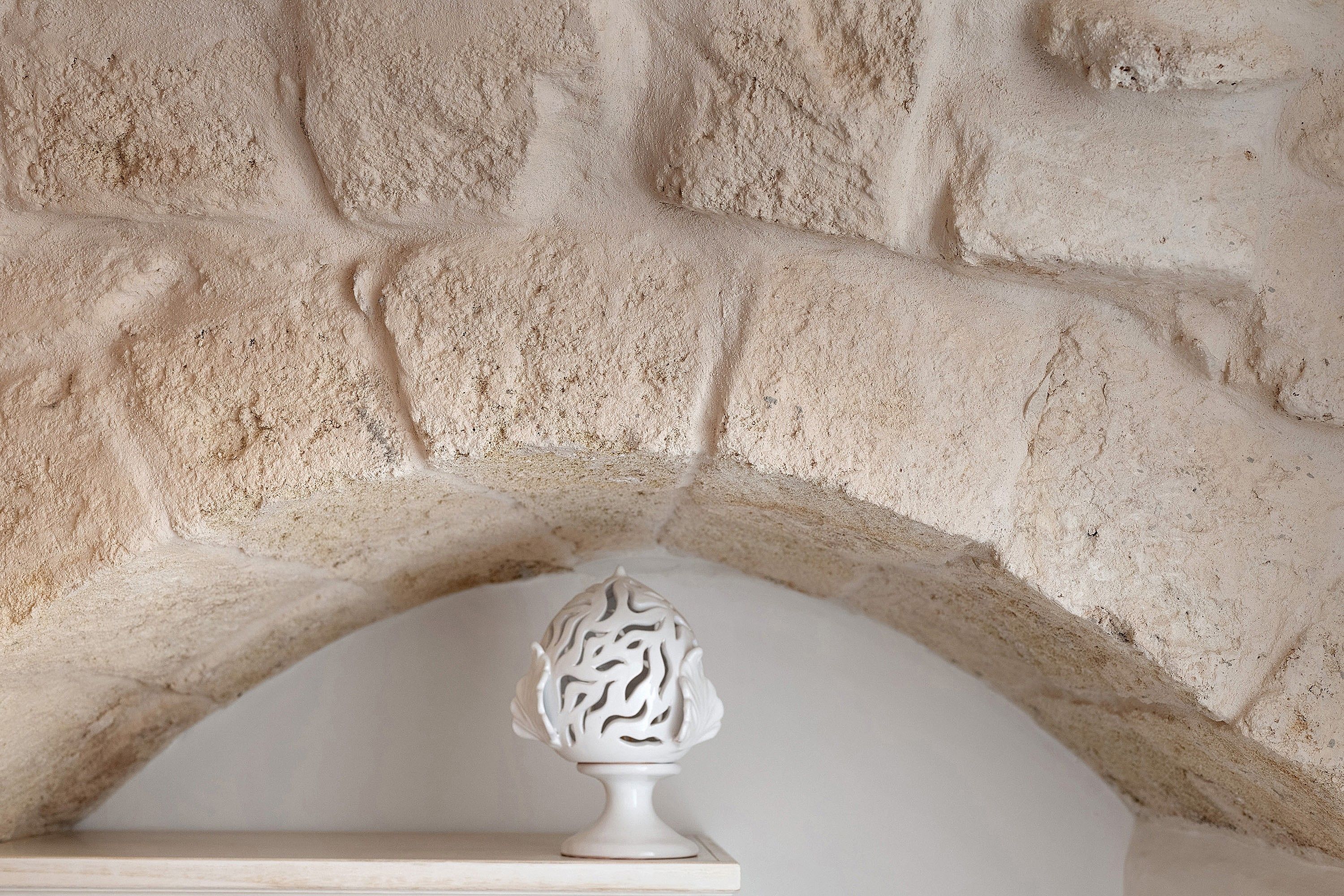 A stone wall with a white decorative object on a shelf.