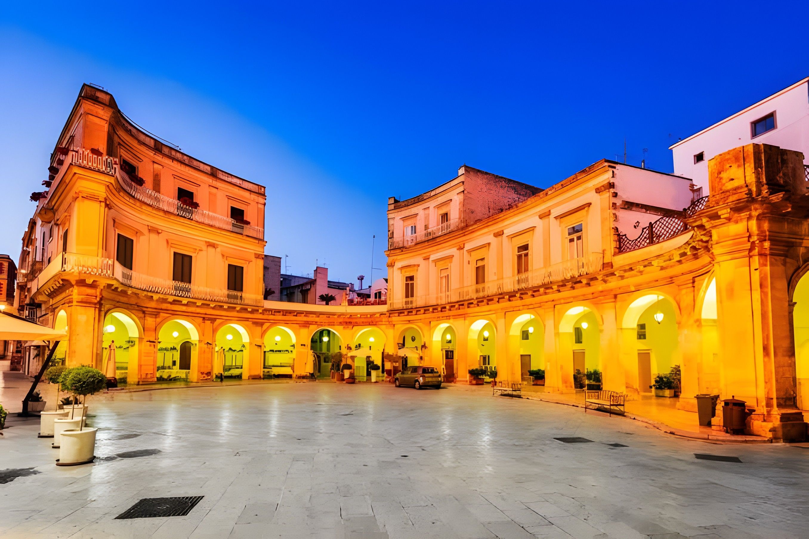 A spacious courtyard with a central open area surrounded by buildings with arched openings.