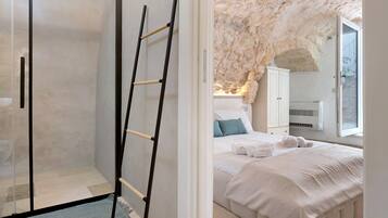 Une chambre avec un lit, une armoire, une échelle et un mur en pierre.