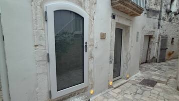 Un bâtiment doté d’une grande porte en arc de cercle, d’un petit balcon et d’une cour pavée de pierres.