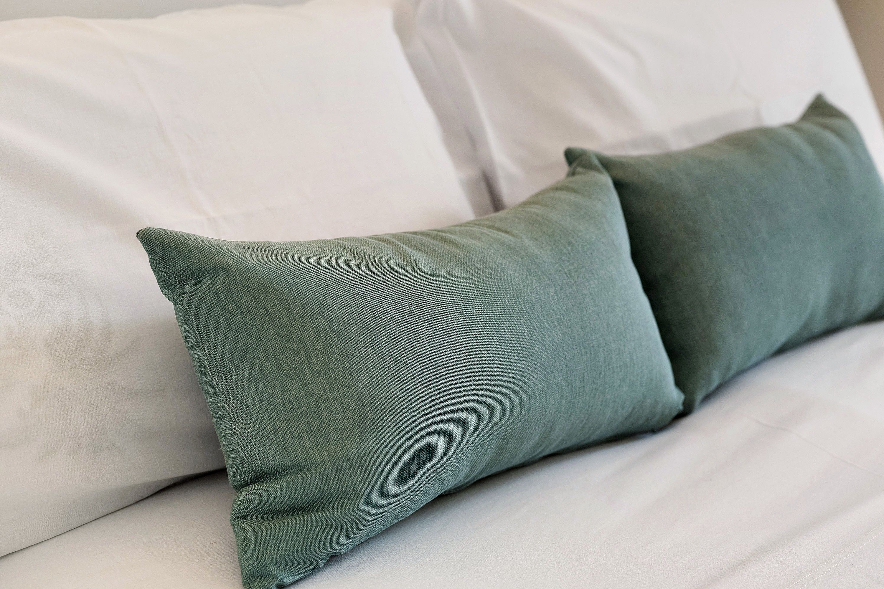 Una parte de una cama con almohadas y un colchón blanco.