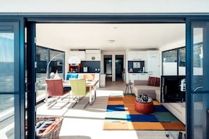 An open-plan living area with a dining table, chairs, a sofa, and a television.