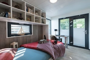 A modern bedroom with a bed, a desk, and a bookshelf.