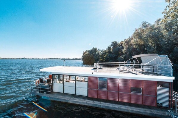 A stationary boat with a covered deck area, seating arrangements, and a railing.