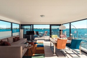 A modern interior with a sofa, dining table, chairs, and a TV.