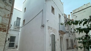 Una calle estrecha con un edificio blanco que tiene un pequeño balcón y una puerta.