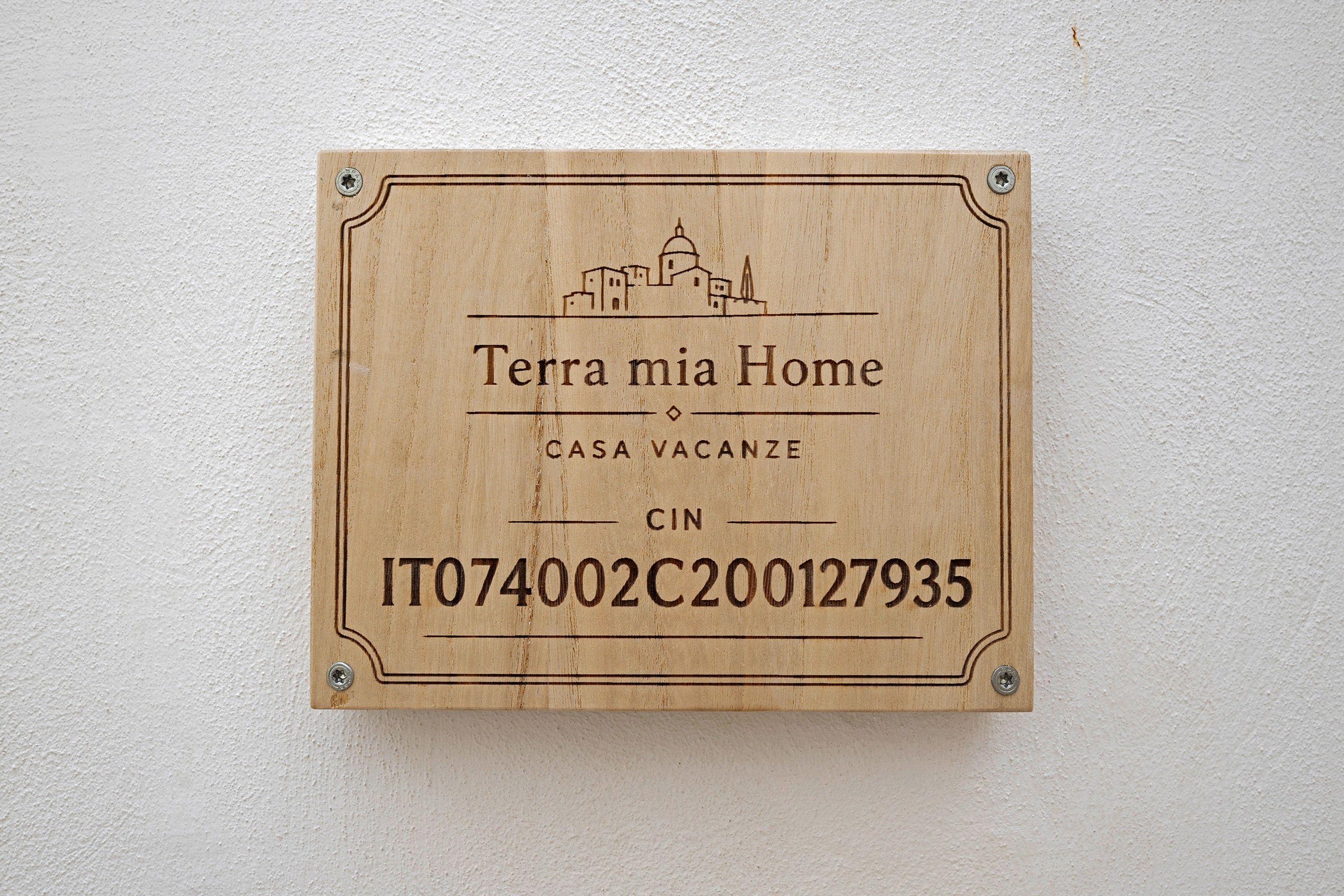 Una placa de madera con el texto 'Terra mia Home' y 'CASA VACANZE', indicando una vivienda vacacional.