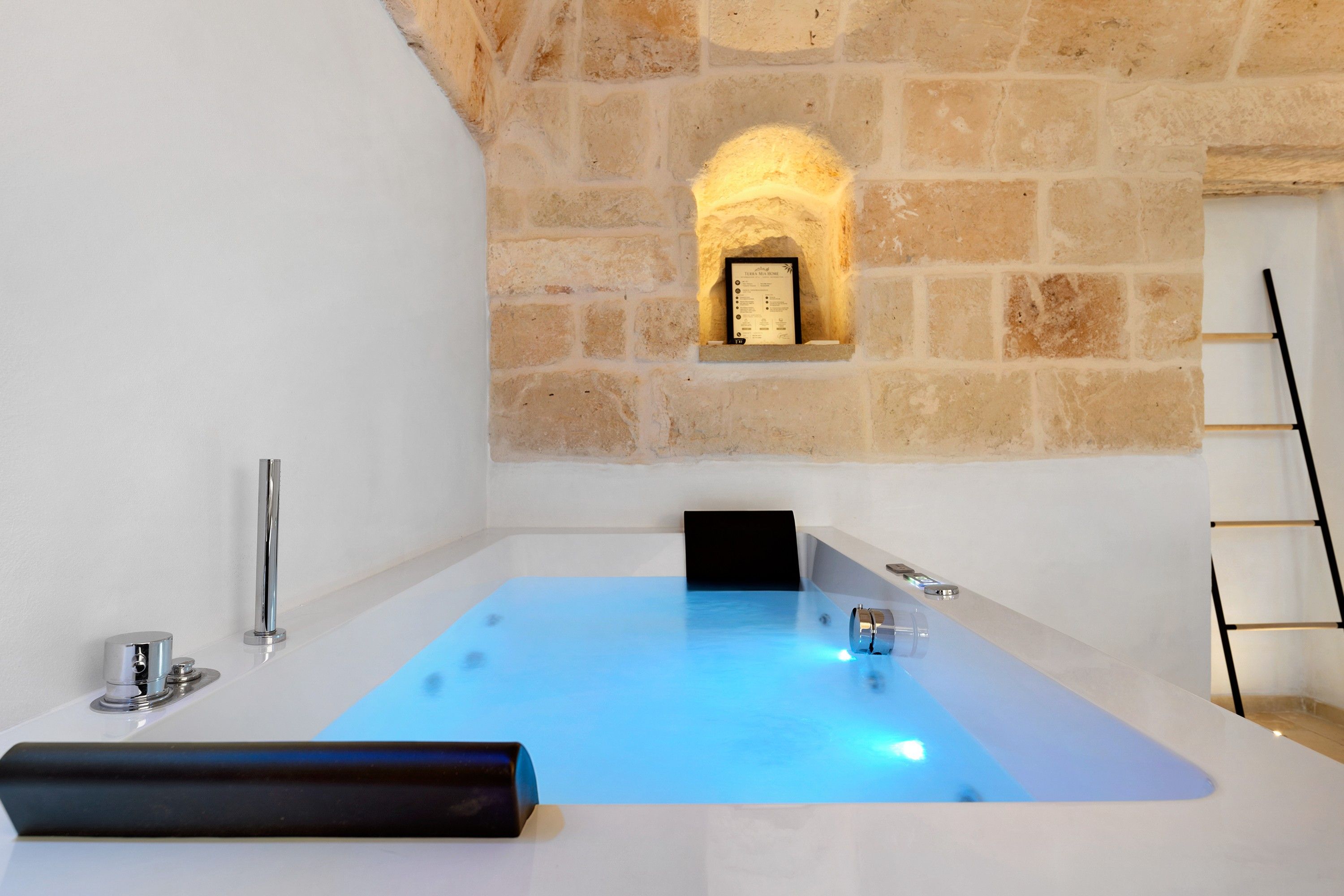 A modern bathroom with a stone wall, a bathtub, and a black towel.