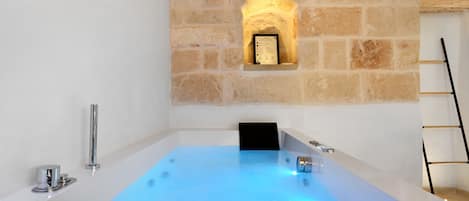 A modern bathroom with a stone wall, a bathtub, and a black towel.
