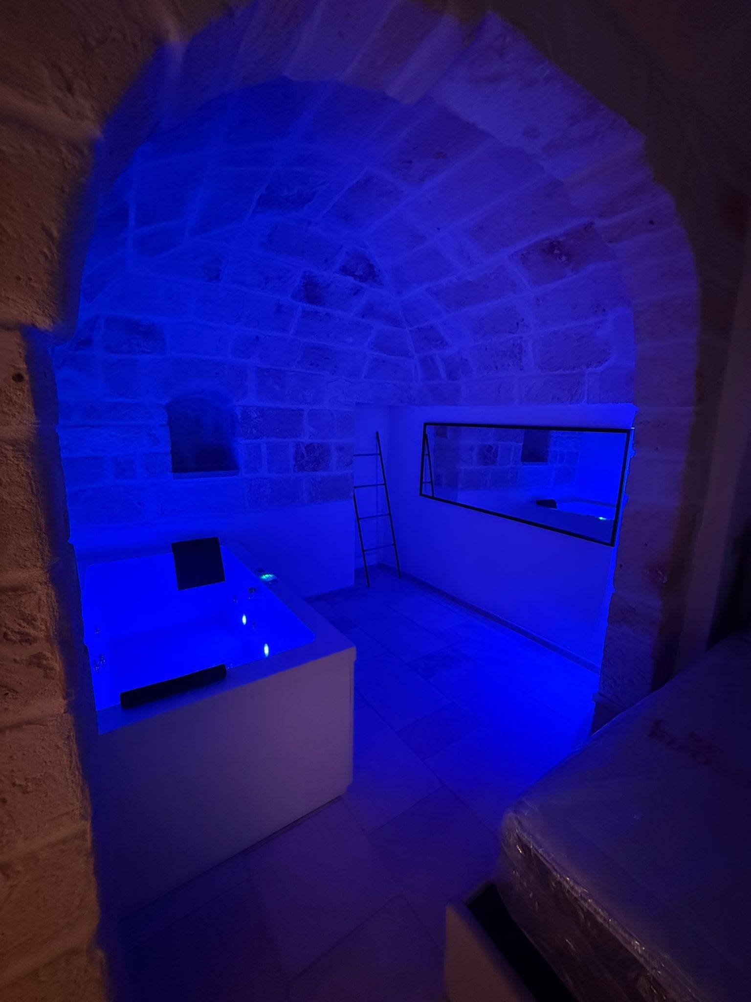 Una habitación con paredes de piedra, una mesa blanca y un banco.