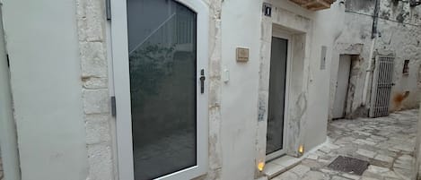 Un edificio con un gran arco de entrada, un balcón pequeño y un patio empedrado de piedra.
