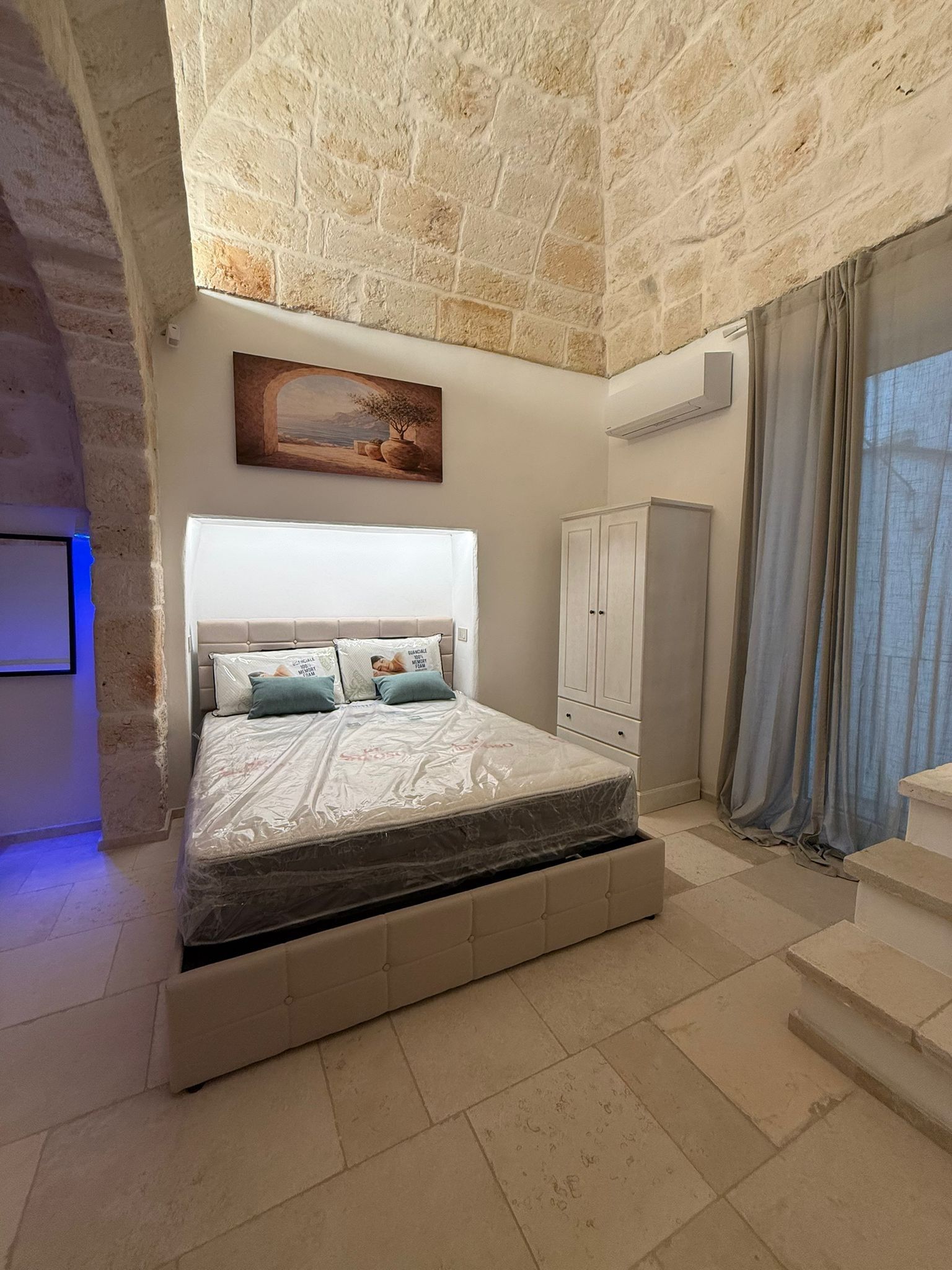 Un dormitorio con cama, armario y un cuadro en la pared.