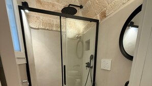 Un baño moderno con cabina de ducha de vidrio, inodoro blanco y tocador de madera con lavamanos.