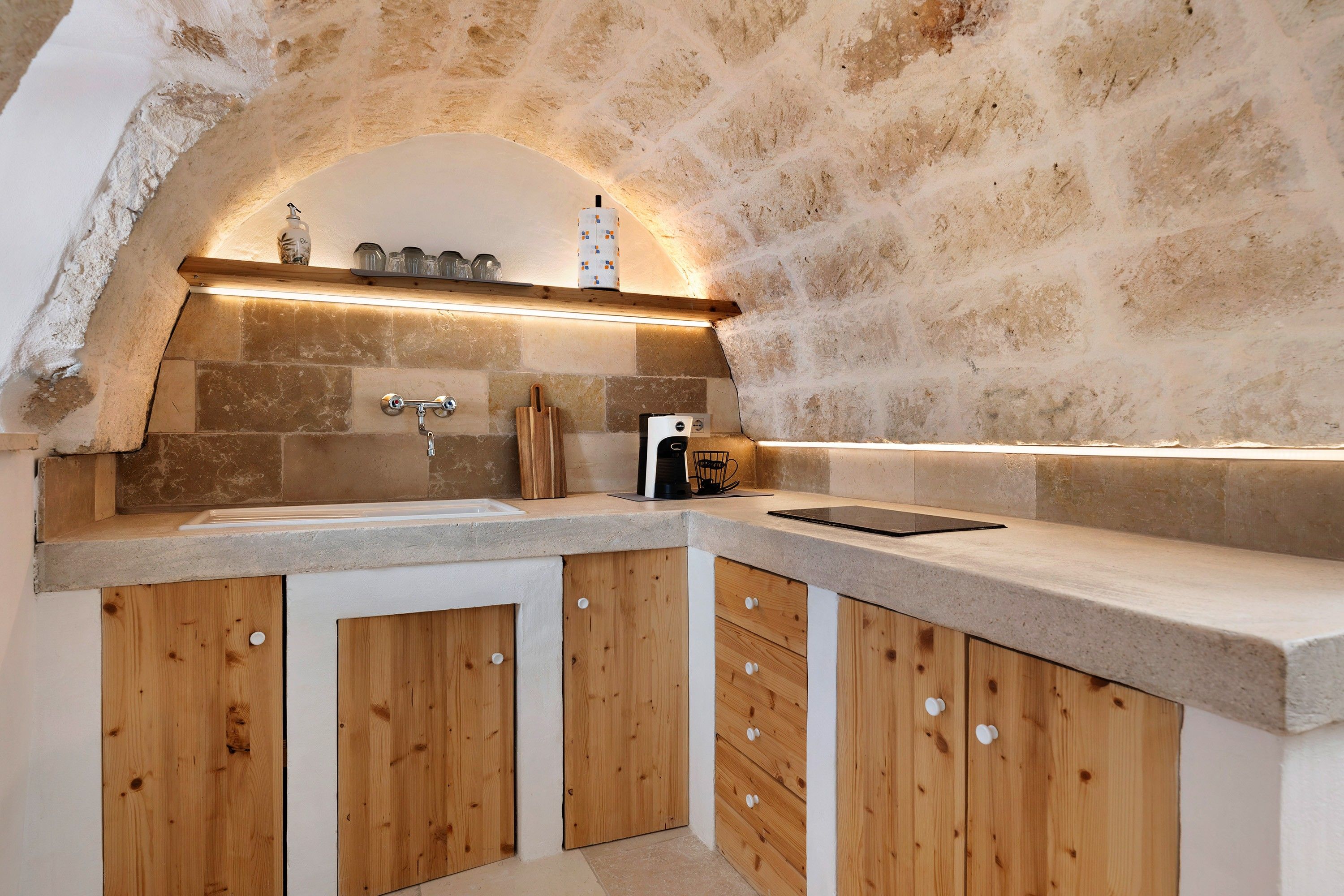 A kitchen with a stone wall, wooden cabinets, and a countertop.