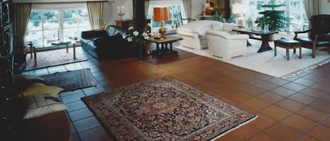 Ein geräumiges Wohnzimmer mit großem Teppich, Sofas und Kamin.