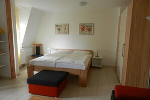 A bedroom with a bed, bedside tables, a bench, and two wall-mounted pictures. - LK 6 Remke in the Liebeskind house (Binz)