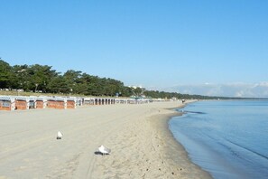 A beach with a row of beach huts, a sandy shore, and a calm sea. - LK 6 Remke in the Liebeskind house (Binz)
