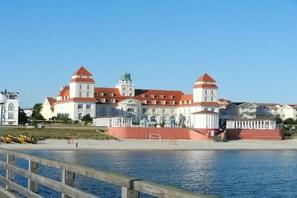 A waterfront building with a prominent tower, a red wall, and a clear sky. - LK 6 Remke in the Liebeskind house (Binz)