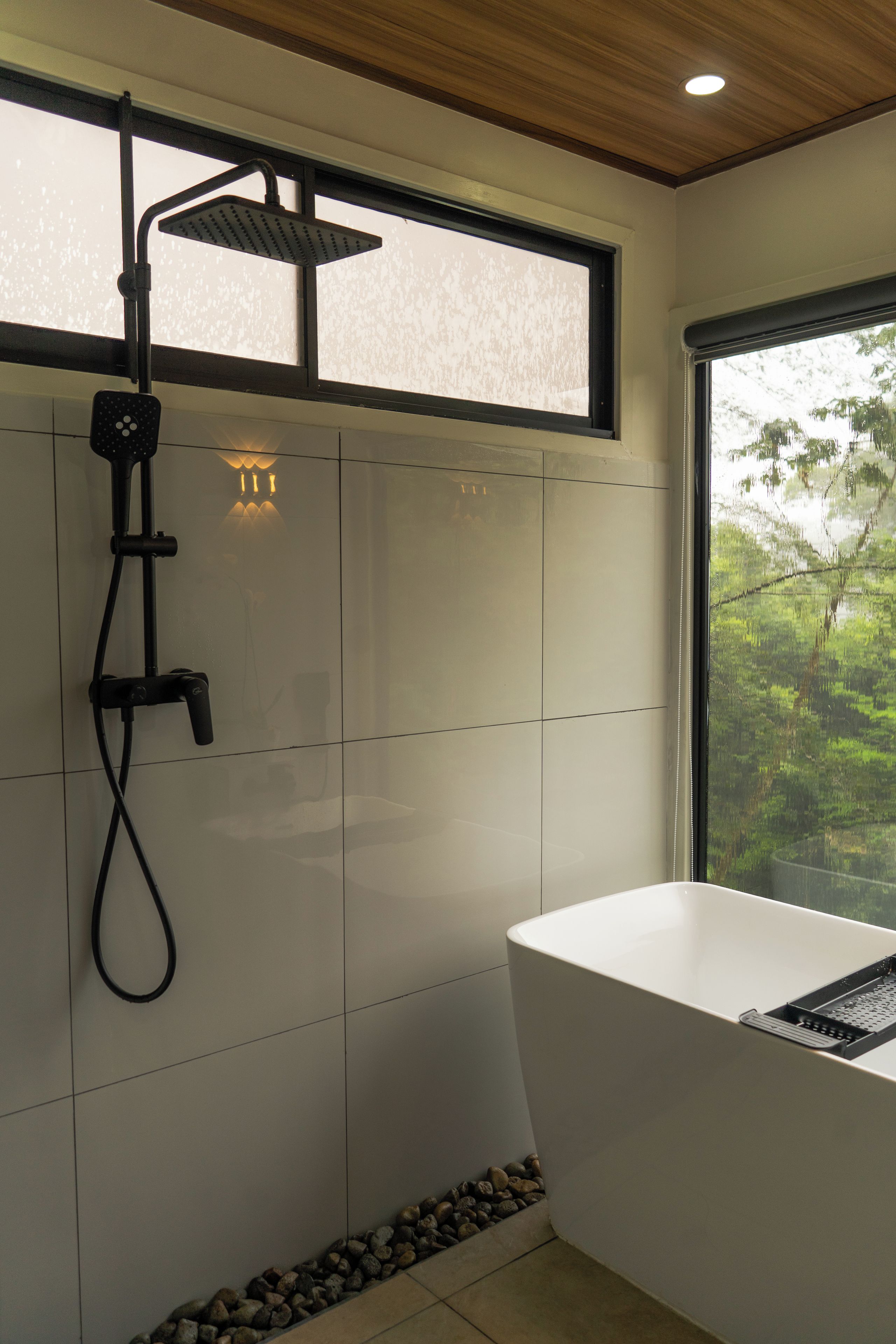 Un baño moderno con ducha, bañera y ventana que ofrece vistas a zonas verdes.