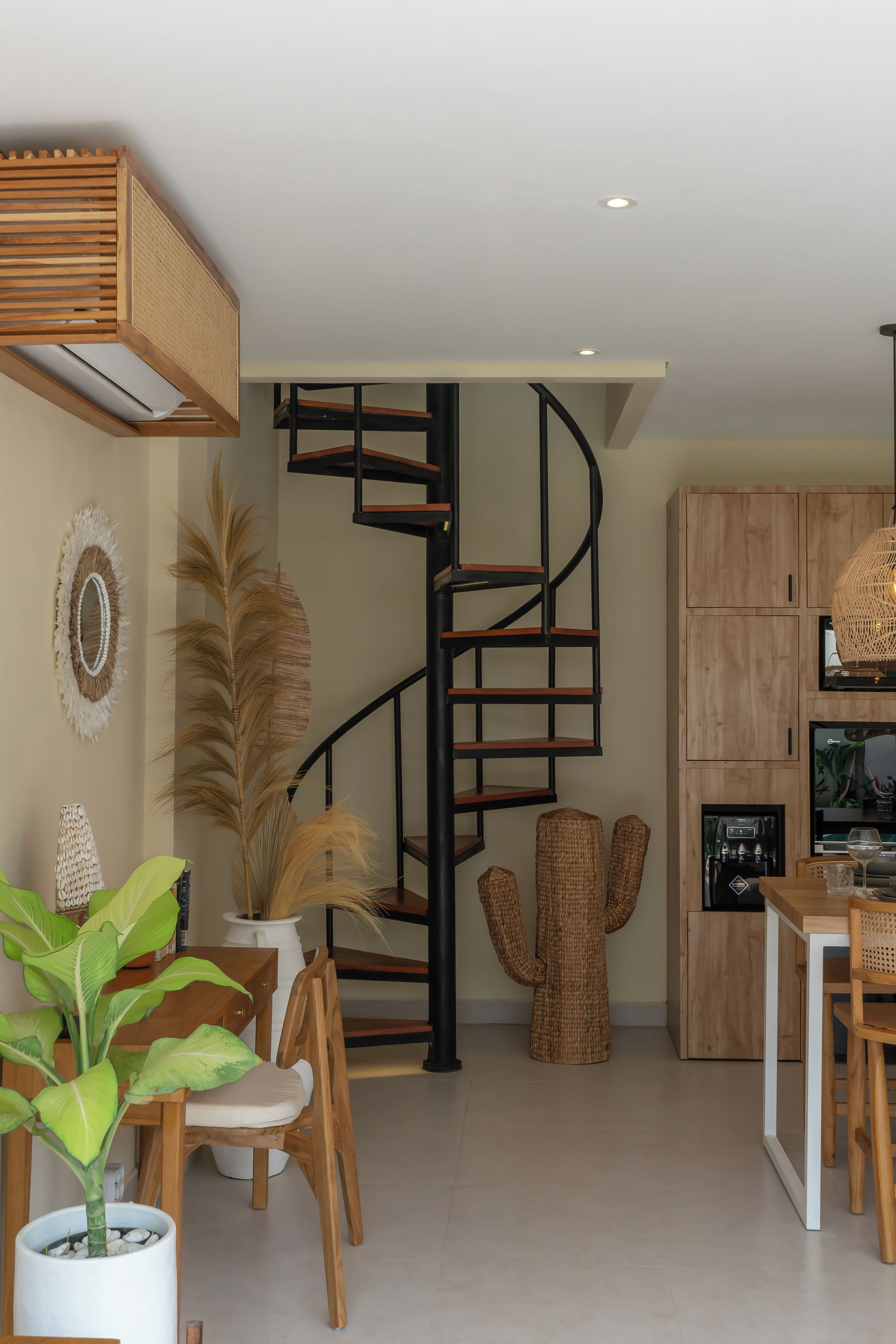 Un interior moderno con una escalera espiral, muebles de madera y una zona de cocina.