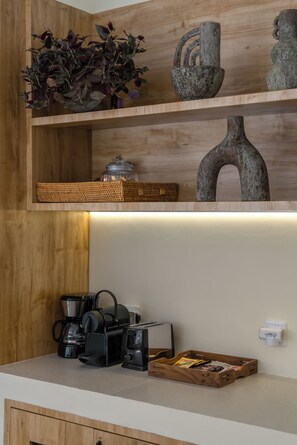 A wooden shelf with decorative vases and a woven basket. Below, there is a coffee maker and a tray with snacks. - Villa Tigana (Pererenan)