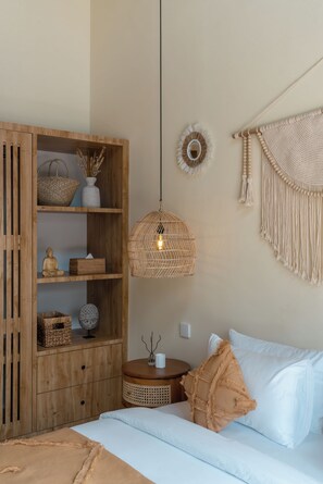 A room with a bed, a wooden wardrobe, a woven hanging light, and a macrame wall hanging. - Villa Tigana (Pererenan)