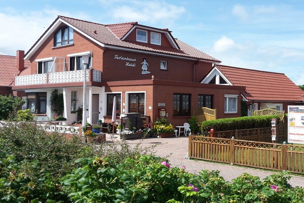 A two-story building with a red-tiled roof, a balcony, and a sign that reads 'Fischerhaus Hotel'.