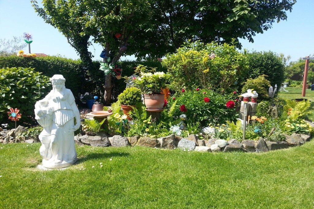 A garden with a statue, potted plants, and a variety of flowers.