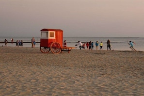 Ein Strand mit einer roten und weißen Rettungswache und einem Holzstand.