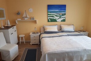 Ein Schlafzimmer mit einem Bett, Nachttischen, einem Schminktisch, einem Stuhl, einer Kommode und einem Bild an der Wand.