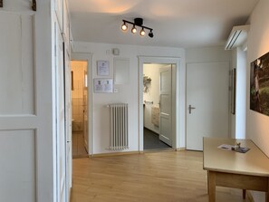 Un couloir avec un radiateur, un plancher en bois et un luminaire au plafond.