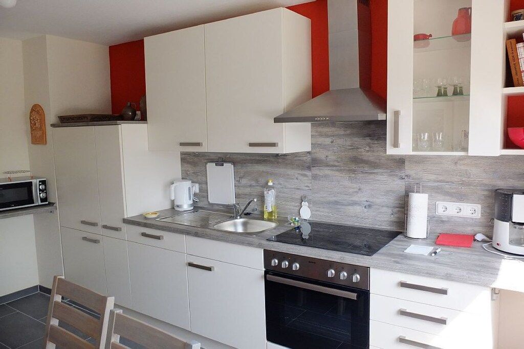 Een moderne keuken met witte kasten, een roestvrijstalen spoelbak, een ingebouwde oven en een magnetron.