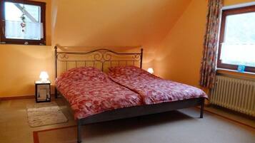 Een slaapkamer met een bed, twee bedlampen, een raam met gordijnen en een radiator.