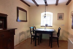 Un coin repas comprenant une table et des chaises, une horloge et une fenêtre laissant entrer la lumière naturelle.