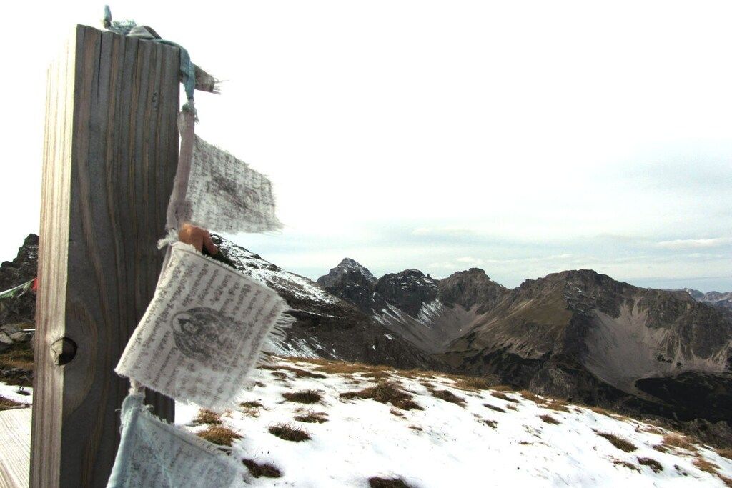 Un poste de madera con un letrero adherido, con montañas al fondo.