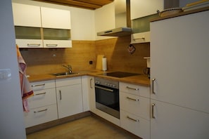 Eine Küche mit weißen Schränken, einer Holz Arbeitsplatte, einer Edelstahl-Spüle und einem eingebauten Backofen.