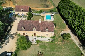Vista aerea di una proprietà con una grande casa, una piscina e una fitta foresta.