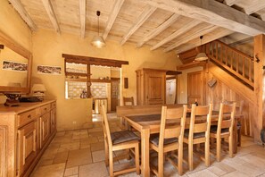 A rustic wooden interior with a dining area, kitchen, and staircase.