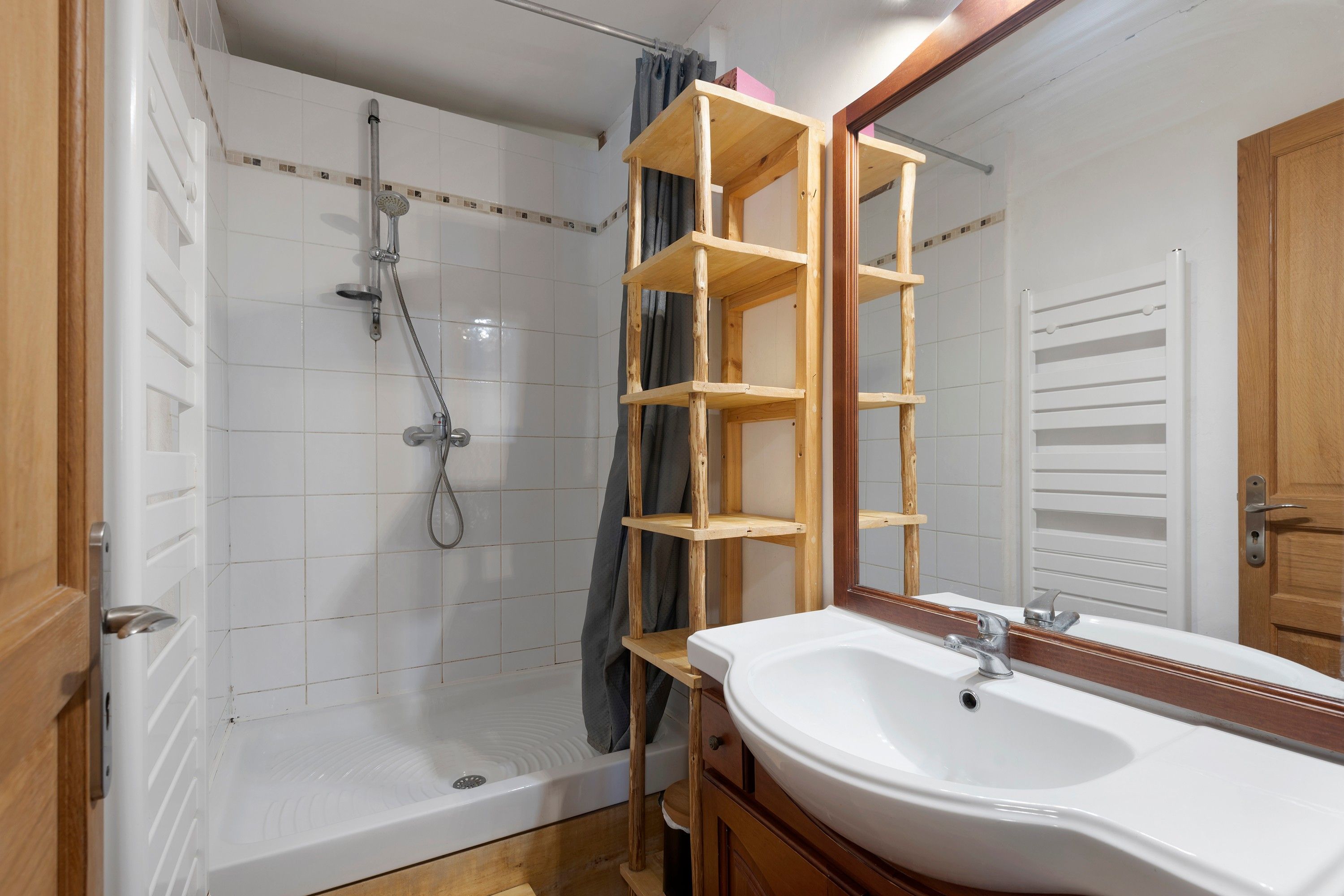 Un baño con ducha, lavamanos y espejo.