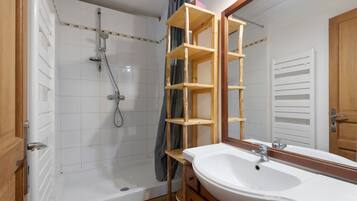 Un baño con ducha, lavamanos y espejo.
