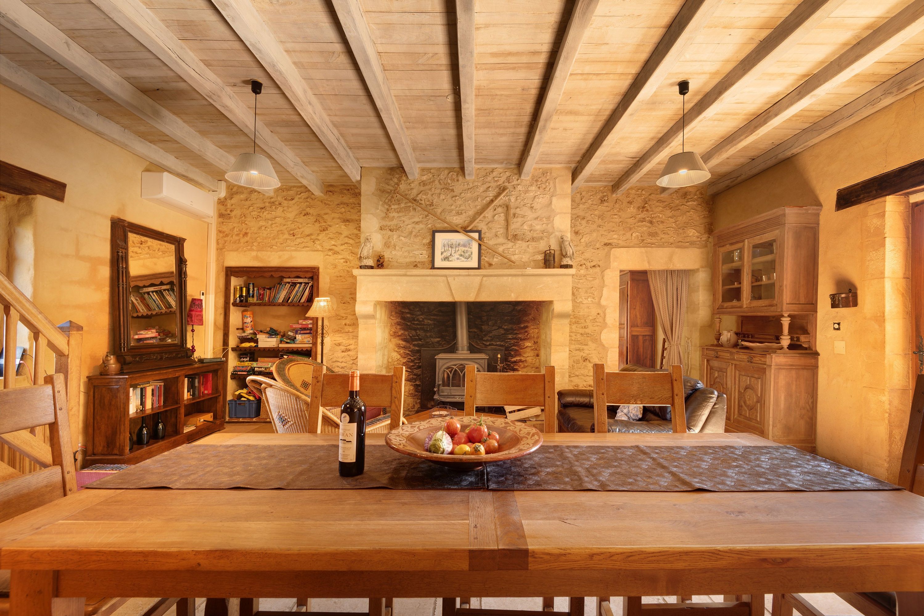 Ein rustikaler Essraum mit Holztisch, Stühlen, Kamin und einer Steinwand.