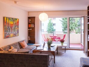 A modern living room with a sofa, coffee table, and a balcony with red chairs. - Colette 42 Appartement/Fewo, Dusche oder Bad, WC 2-Zimmerwohnung by Interhome (Davos)