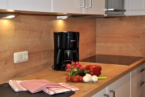 A kitchen with a coffee maker, a wooden countertop, and some vegetables. - 2 in the country house Magdalena (Oberstdorf)