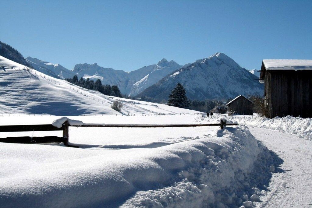 A snow-covered mountain landscape with a wooden building and a wooden fence.
