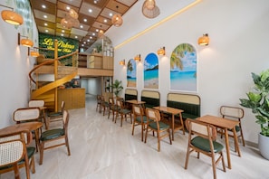 Un restaurante con una escalera en espiral, mesas y sillas de madera, y decoración de temática tropical.