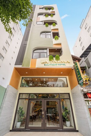 Um hotel boutique de vários andares com fachada moderna, grandes janelas e uma placa indicando ser um hotel boutique.