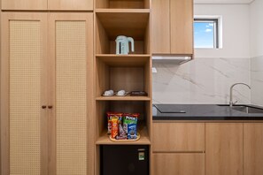 A kitchen with wooden cabinets, a black refrigerator, and a window above the sink. - La Palma Boutique Hotel Da Nang (an hai)