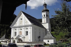 A white church with a bell tower and a small annex. - Spitzstein on the Bergerhof (Aschau im Ch. \/Sachrang)